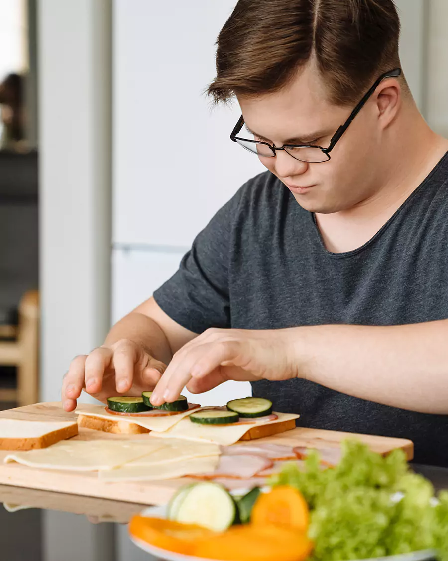 Disabled man with down syndrome making at sandwich at home