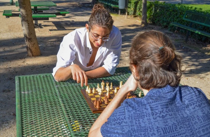 Two friends playing chess outside in park